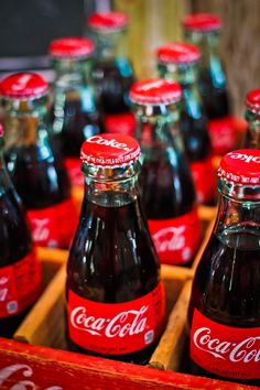 coca - cola bottles are lined up in a wooden box