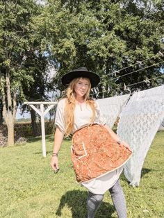 a woman in a hat and dress is holding an old fashioned quilt on a clothes line