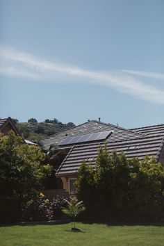 an image of a house that has solar panels on the roof and some bushes in front of it