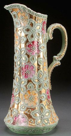 an ornately decorated pitcher with pink flowers on it