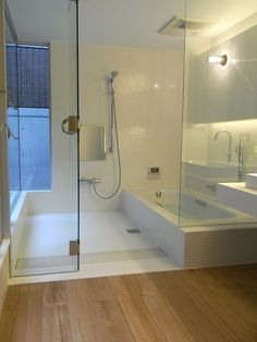 a bathroom with a glass shower door and wooden flooring, along with two sinks