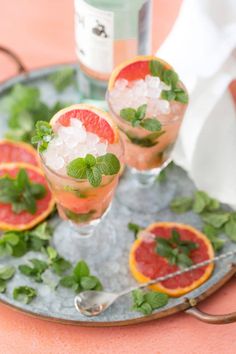 grapefruit and mint spritkled cocktails on a metal tray with ice