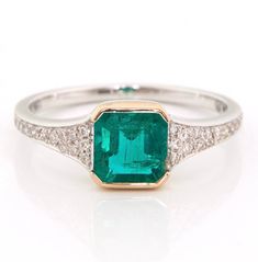 an emerald and diamond ring on a white background