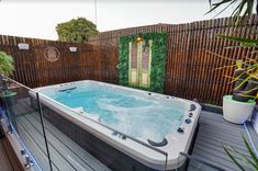 a large hot tub sitting on top of a wooden deck next to a green wall