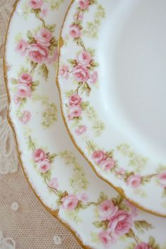 two plates with pink flowers on them sitting on a table