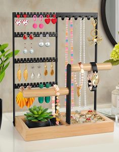 an assortment of jewelry is displayed on a shelf in front of a mirror and potted plant