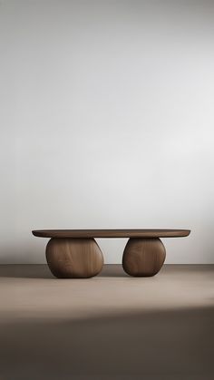 an oval wooden table sitting on top of a brown floor next to a white wall