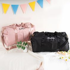 two duffel bags sitting on top of a bed next to flowers and bunting