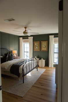 a bed room with a neatly made bed next to a window and a ceiling fan