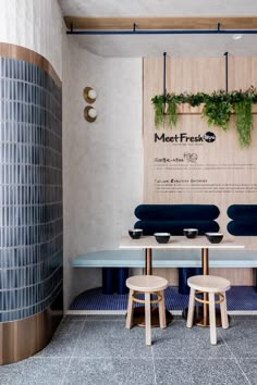 an indoor dining area with blue and white tiles on the walls, wooden tables and stools