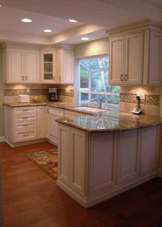 a large kitchen with white cabinets and wood flooring, along with an island in the middle