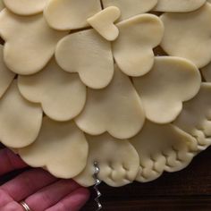 a close up of a person's hand holding a pastry with hearts on it