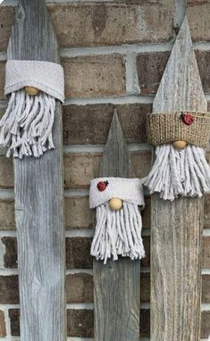 two wooden gnomes made out of old boards are hanging on a brick wall and one is wearing a knitted hat