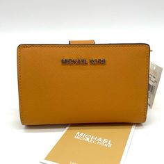 Brand New With Tag Michael Kors Medium Bifold Wallet 100% Leather From Tanneries Meeting The Highest Standards Of Environmental Performance Wallet Crossgrain Leather 100% Leather Color: Cider Gold-Tone Hardware 5.25"W X 3.5"H X 1.25"D Interior Details: 1 Zip Pocket, 3 Slip Pockets, 6 Card Slots, Id Window Lining: 100% Polyester Snap Fastening Dust Bag Not Included Imported Yellow Leather Rectangular Wallet, Yellow Leather Travel Wallets, Everyday Michael Kors Bifold Wallet, Michael Kors Leather Bifold Bag, Classic Yellow Rectangular Wallet, Michael Kors Leather Wallet For Daily Use, Michael Kors Gold Wallet For Everyday Use, Michael Kors Leather Wallets, Gold Michael Kors Wallet For Everyday Use