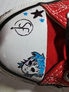 a pair of red and white shoes with cartoon drawings on the soles, sitting on top of a piece of paper