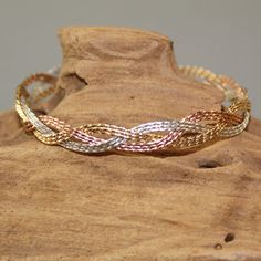 Three strands each of 14kt yellow gold filled, 14kt rose gold filled, and sterling silver, twisted and plaited in a beautiful, flowing braid. A stunning bracelet that is sure to get noticed! And amazing gift for that special woman...for an anniversary, birthday, Mother's Day, or Christmas. A delightful treat for yourself as well! Stackable with many of my other wirewrapped bracelets. The hook and eye clasp is easy to get on and off yourself. Choose your size from the variations for a perfect cus Metal Braided Bangle Bracelet For Gift, Adjustable Rose Gold Braided Bracelet, Adjustable Gold Woven Braided Bracelet, Gold Hand-strung Braided Bracelets, Multicolor Hand-strung Braided Bangle Bracelet, Twisted Wire, Stackable Bracelets, Braided Bracelets, Gold Bangles