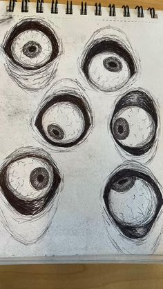 a drawing of five circles with one eye open and the other half closed, on top of a wooden table