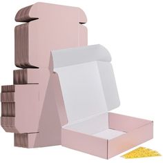 an open pink box sitting on top of a pile of cardboard boxes next to a piece of yellow paper