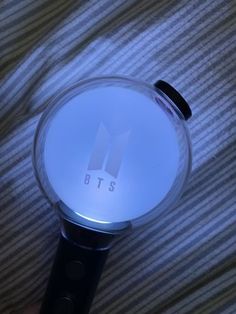 a close up of a person's hand holding a glass object with the letters bts on it