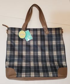 a plaid bag hanging on the wall with a tag