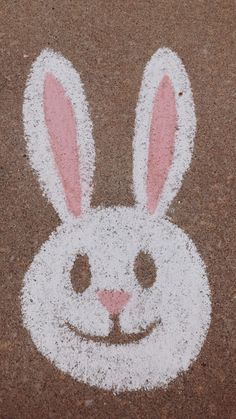 a bunny face drawn on the ground with white paint and pink ears in front of it