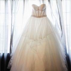 a white wedding dress hanging in front of a window