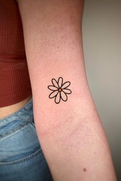 a woman's arm with a small flower tattoo on it