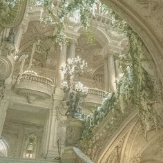 an ornate building with chandeliers and statues on the walls, in front of a staircase