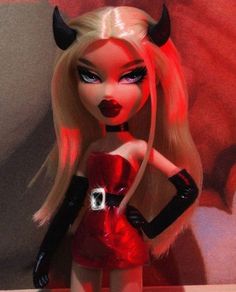 a doll is dressed up as a devil with horns on her head and red dress