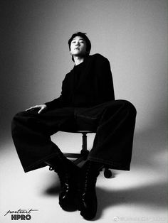 a man sitting on top of a chair in black and white