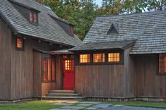 two brown wooden houses with red doors and windows on each side, along with stone steps leading up to the front door