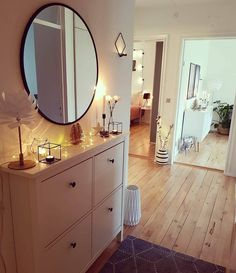 a white dresser sitting next to a mirror on top of a wooden floor