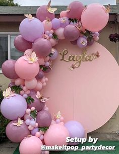 a pink and purple balloon arch with butterflies on it