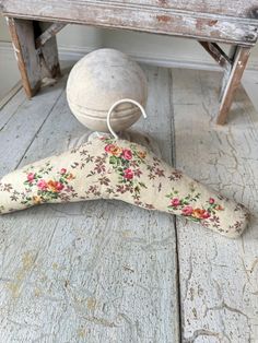 an old wooden bench with a flowered pillow and ball sitting on top of it