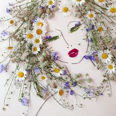 a woman's face surrounded by daisies and wildflowers, with a red lip