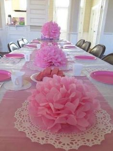 the table is set with pink flowers and place settings for guests to sit down at