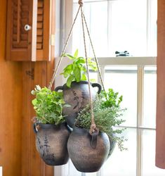 three hanging planters filled with plants on a window sill in front of a door