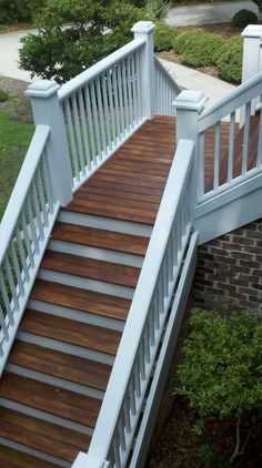 a wooden deck with white railing and handrails