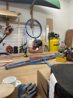 a man working in a shop with tools and equipment on the table next to him