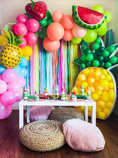 a party with balloons, pineapples, watermelon and rainbow streamers