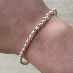 a close up of a person wearing a gold bracelet with pearls on the end of it