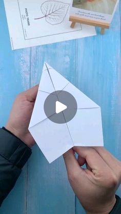 someone is holding an origami envelope over a blue wooden table with pictures on it