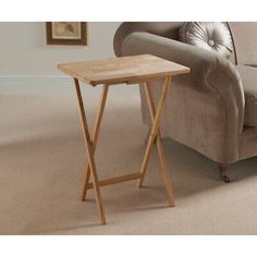 a small wooden table sitting on top of a carpeted floor next to a couch