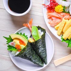 two plates with sushi on them next to a cup of coffee