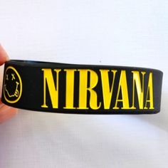 a person holding up a black and yellow name tag that says nirvana on the front