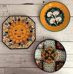 three plates with designs on them sitting on a white wooden table next to each other