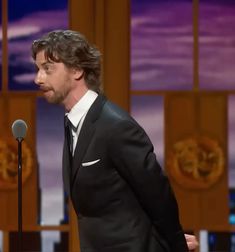 a man in a tuxedo standing next to a microphone