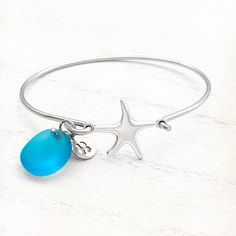 Carry a piece of the ocean wherever you go with the Starfish Sea Glass Charm Bracelet. This enchanting piece captures the essence of the shore, featuring delicate charms of shimmering sea glass and a beautifully detailed starfish. Each element of this bracelet tells a story of beachside walks, salty breezes, and sunlit waves. The soft hues of the sea glass evoke the colors of the ocean, while the starfish charm reminds us of nature's treasures hidden beneath the tide. Perfect for layering or wea Elegant Starfish Bracelets For Beach, Elegant Starfish Bracelet For Gift, Turquoise Bracelet With Starfish Charm As Gift, Adjustable Ocean-inspired Metal Jewelry, Ocean-inspired Silver Glass Jewelry, Silver Starfish Bracelet For Gift, Silver Starfish Bracelet, Ocean-inspired Starfish Bracelets As Gifts, Ocean-inspired Bangle Jewelry For Gifts