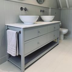 two white bowls on top of a gray vanity in a bathroom next to a toilet