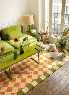 a living room filled with furniture and flowers on top of a wooden floor next to a window